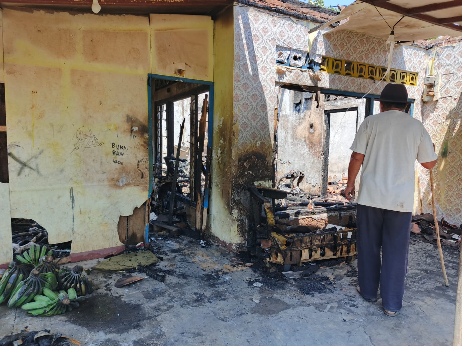KEBAKARAN: Sejumlah warga sedang melihat bangunan rumah milik Andeh yang telah ludes terbakar api.