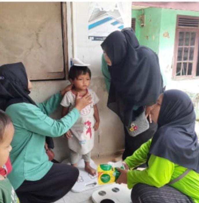 PENIMBANGAN ANAK: Pengukuran dan penimbangan berat badan anak oleh kader Posyandu Karyasari. 