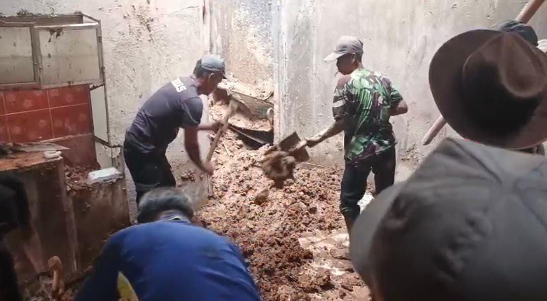 GOTONG ROYONG: Warga dan aparat desa bergotong royong membersihkan material longsor yang menimbun rumah warga.