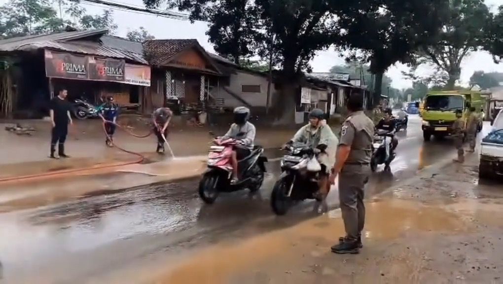 ‎BERSIHKAN JALAN: Petugas pemadam kebakaran (Damkar) Purwakarta sedang membersihkan material tanah merah yang berceceran di Jalan Cilalawi.